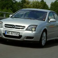 Srebrny Opel Vectra C 1.9 CDTI 150KM jedzie po drodze, otoczony zielenią.