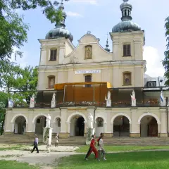 Kalwaria Pacławska: Sanktuarium z kopułami i tarasem, gdzie pielgrzymi spacerują pośród zieleni.