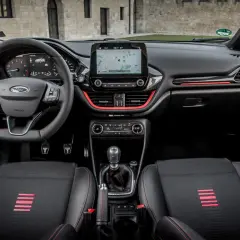 Interior deportivo del Ford Fiesta ST Line. Volante, asientos y detalles rojos resaltan en este habitáculo moderno.