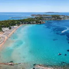 Traumhafter Strand bei Athen mit türkisfarbenem Wasser, Liegestühlen und Booten.
