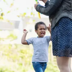 Un niño de 4 años, mi hijo, no obedece y pega. Llora y se enfada mientras su madre intenta calmarlo.