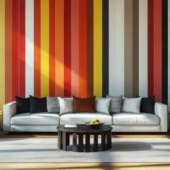 Salon moderne avec un mur au motif rayures multicolores vives. Un canapé blanc, des fauteuils gris et une table basse complètent l'ensemble.