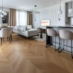 Elegancka jodełka z paneli winylowych, której grubość podkreśla jakość. Salon z sofą, jadalnia i barek kuchenny.