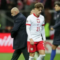 Piłkarz Polski z numerem 21 i trener patrzą w dół po przegranym meczu z Chorwacją.