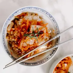 Miseczka ryżu z pikantnym kimchi i marchewką, idealne danie. Pałeczki czekają, by spróbować, z czym jesc kimchi.