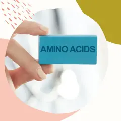 Dłoń trzyma niebieski klocek z napisem "AMINO ACIDS". Kluczowe składniki w kosmetykach dla zdrowej skóry.