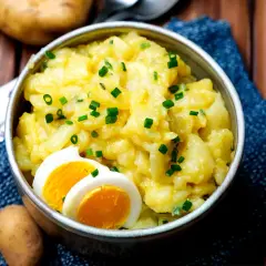 Omas Kartoffelsalat, cremig und herzhaft, garniert mit Schnittlauch und gekochtem Ei. Ein Klassiker, der immer schmeckt.