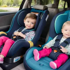 Zwei lächelnde Kinder sitzen sicher in ihren Kindersitzen im Auto.