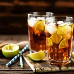 Dwa szklanki z lodem i plasterkami limonki, idealne orzeźwiające drinki na upalny dzień.