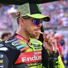 Fabio Di Giannantonio, piloto de MotoGP, bebe de una botella con un tubo, luciendo su casco y gafas de sol.