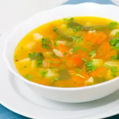 Aksamitna zupa jarzynowa z marchewką, fasolką i ziemniakami, posypana natką. Idealne jakie przyprawy do zupy jarzynowej? Sól, pieprz, majeranek i liść laurowy.