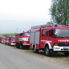 Reihe von roten Feuerwehrfahrzeugen, darunter 9 Fahrzeugtypen der Feuerwehr, bereit für den Einsatz.