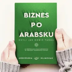 Dwie dłonie trzymają zieloną książkę z białym napisem "Biznes po arabsku".