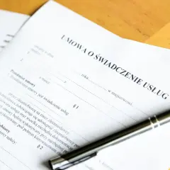 Umowa o świadczenie usług. Czy świadczenie integracyjne wlicza się do stażu pracy? Długopis leży na dokumencie.