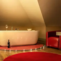 Romantyczny weekend w Kazimierzu Dolnym dla dwojga: wanna, świece, wino i czerwony fotel tworzą idealną atmosferę.