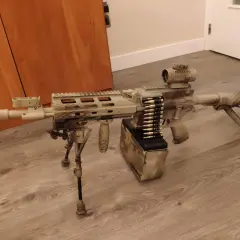 Réplica de airsoft con camuflaje personalizado. El detalle de pintar replica airsoft es impresionante, con un cargador de cinta y mira holográfica.