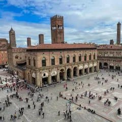 Tłum ludzi na Piazza Maggiore w Bolonii, podziwiający zabytkowe budynki i wieże. To serce miasta i jego główne bolonia atrakcje.