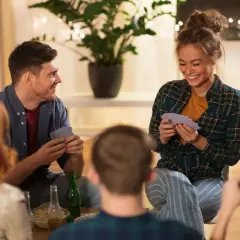 Freunde spielen Karten und lachen. Sie diskutieren die top ten spiel fragen, während sie sich entspannen.