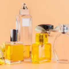 Kilka eleganckich flakonów z perfumami, w tym jeden z żółtym płynem i kwiatową ozdobą. Woda toaletowa ile ma procent? To zależy od jej stężenia.