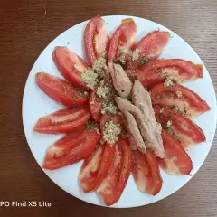 Rodajas de tomate fresco aliñado con ajo picado y hierbas, coronado con trozos de melva. Un plato sencillo y delicioso.