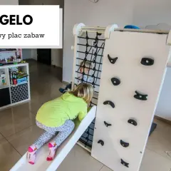 Dzieci bawią się na domowym placu zabaw Figelo. Dziewczynka zjeżdża ze zjeżdżalni, a chłopiec jest w środku konstrukcji.