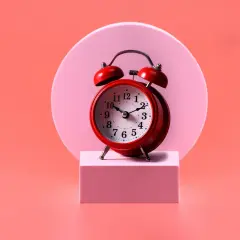 Reloj rojo sobre pedestal rosa. El 0909 significado espiritual nos recuerda la importancia del tiempo y la conexión.