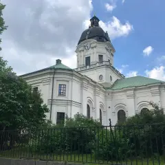 Adolf Fredriks kyrka i Stockholm, en vit kyrka med grön kupol och tak, omgiven av träd och buskar.