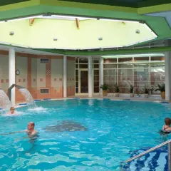 Basen rehabilitacyjny z hydromasażem i wodospadami, w którym kąpią się ludzie.