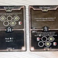 Dwie karty z gry planszowej Gloomhaven: "Auto Turret" i "Gas Canister", przedstawiające ikony akcji i statystyki postaci.