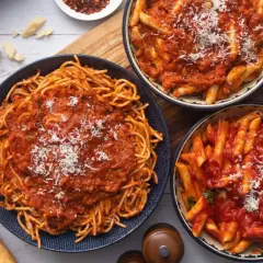 Pyszny obiad bez mięsa: spaghetti i penne w sosie pomidorowym, posypane parmezanem. Idealne dla wegetarian.