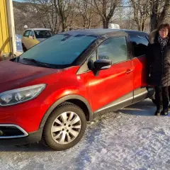 Ett par står bredvid en röd Renault Captur med frost på vindrutan. Kanske ett problem med att starta bilen i kylan?
