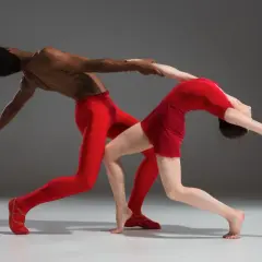 Dwoje tancerzy w czerwonych strojach, w dynamicznej pozie, oddaje ducha **modern jazz**.