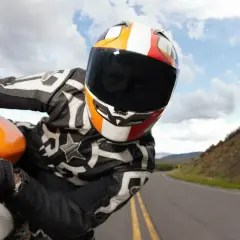 Motociclista con casco y visera oscura, listo para una multa por exceso de velocidad en la carretera.