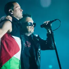 Dwóch mężczyzn na scenie, jeden z flagą Palestyny, drugi śpiewa do mikrofonu. To fragment koncertu z męskie granie piosenki.