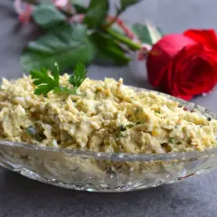 Pyszna pasta z awokado i tuńczyka, udekorowana natką pietruszki, w kryształowej misie. W tle czerwona róża.