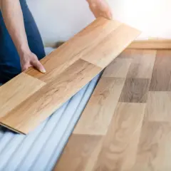 Ręce układają drewniany panel podłogowy. Proces jak wymienić panel w środku, aby odnowić podłogę.