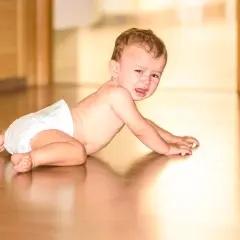 Płaczący niemowlak w pieluszce na podłodze. Czy to pierwsze oznaki adhd u niemowlaka, czy po prostu zły humor?