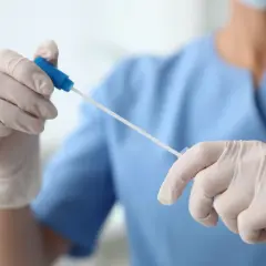 Ręce w rękawiczkach przygotowują wymaz z cewki moczowej.
