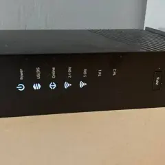 Czarny router Arris z widocznym przyciskiem WPS i wskaźnikami statusu: Power, US/DS, Online, 2.4 GHz, 5 GHz, Tel 1, Tel 2.