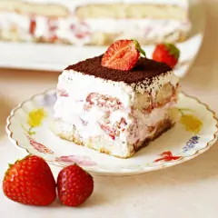 Pyszne tiramisu truskawkowe z bitą śmietaną, biszkoptami i świeżymi truskawkami, posypane kakao.