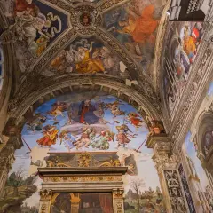 Affreschi celestiali adornano la volta di una chiesa a Roma, con angeli e figure bibliche che danzano tra nuvole e architetture dipinte.
