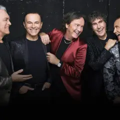 Cinque uomini sorridono, uno con giacca rossa, ricordando i testi di Renato Zero "Qualcuno mi renda l'anima".