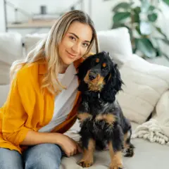 Uśmiechnięta blondynka i jej piesek siedzą na kanapie. Może dlatego pies chodzi za mną krok w krok, bo czuje się bezpiecznie?