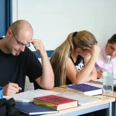 Konzentrierte Studierende beim lateinischen Fernstudium, vertieft in ihre Unterlagen.