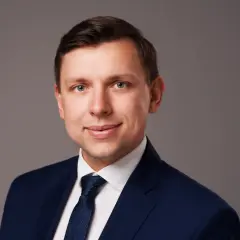 Portret mężczyzny w granatowym garniturze i białej koszuli z krawatem.