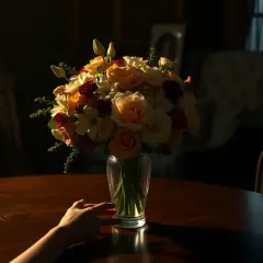 Sennik kwiaty bukiet róż i lilii w wazonie, ręka dotyka stołu.
