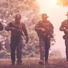 Czterech żołnierzy w kamuflażu, z karabinami, idzie przez las. Czy to przygotowanie do "Escape from Tarkov wymagania"?