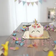 En förtrollande unicorn tårta står på ett träbord, omgiven av konfetti och serpentiner. En magisk födelsedagsfest!