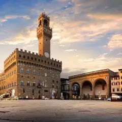 Il maestoso Palazzo Vecchio domina Piazza della Signoria, con la sua torre imponente che svetta nel cielo al tramonto.