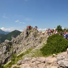 Grupa turystów odpoczywa na skalistym szczycie, podziwiając widok na dolinę Białego Potoku.